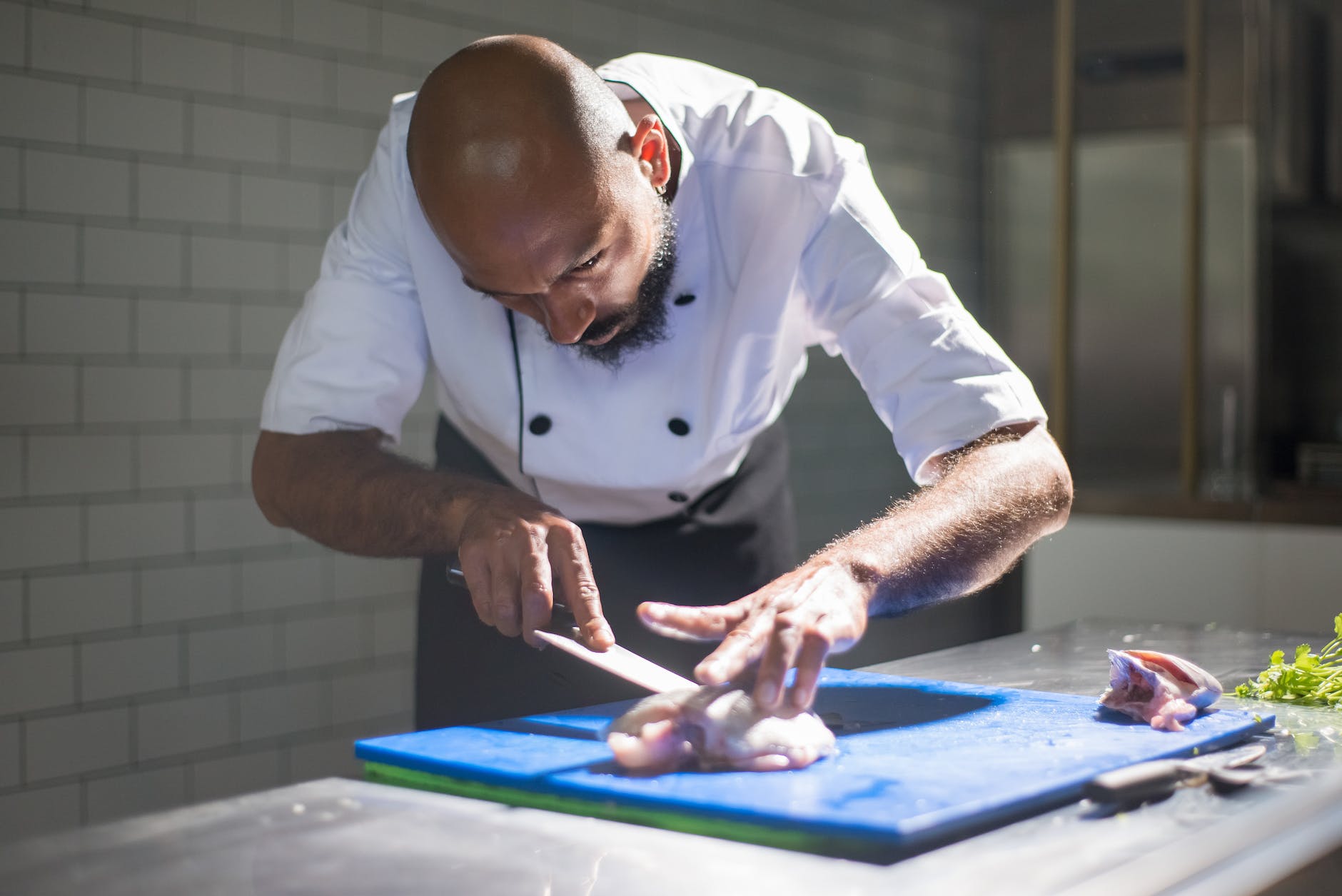 man in white chef slicing a meat