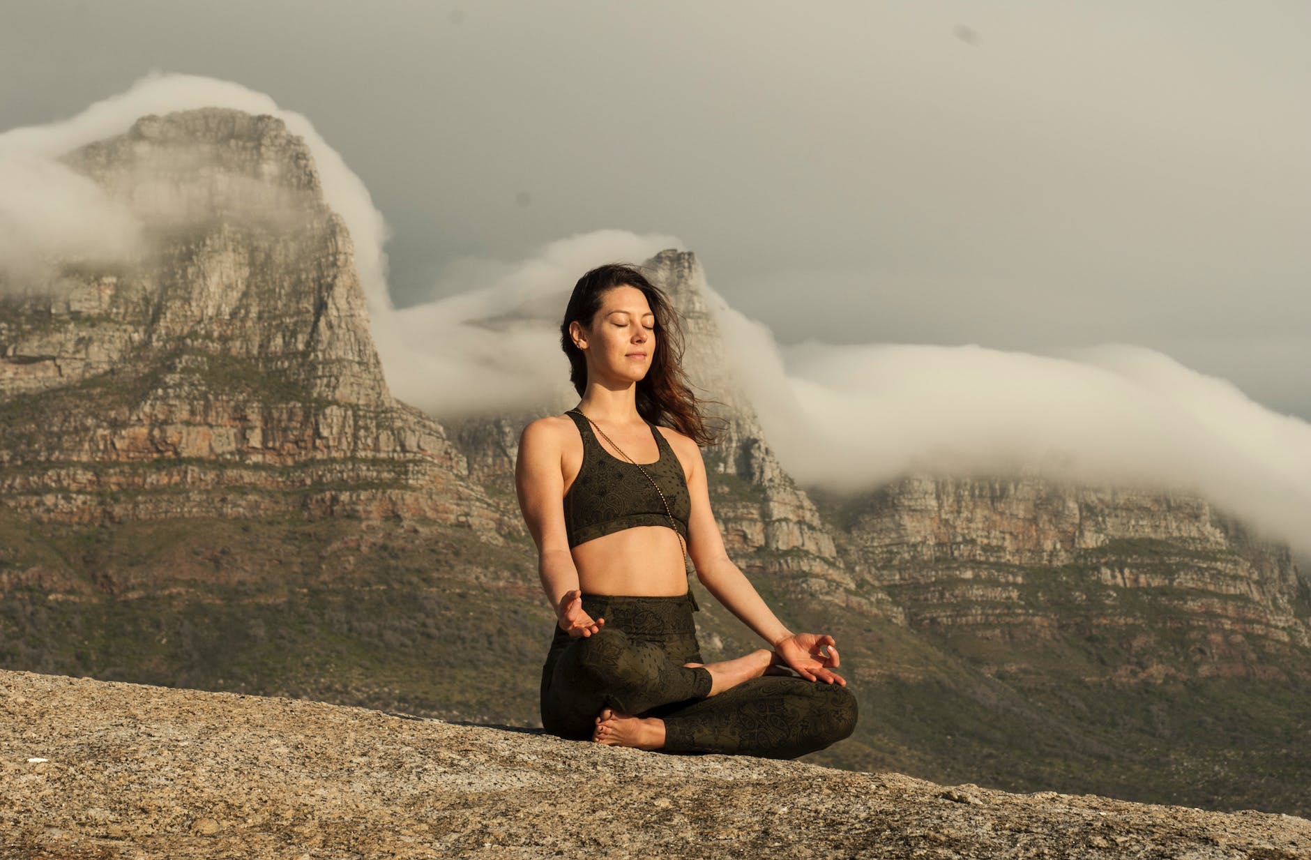 woman in black sports bra and black pants sitting on rock